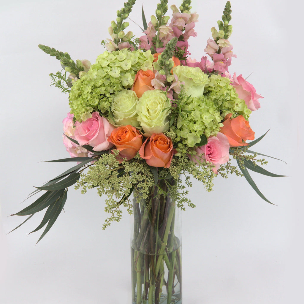 Irreplaceable™ Luxury Bouquet - Vase of pink, peach, and green roses, with green and pink hydrangea blooms, snapdragons, bupleurum, seeded eucalyptus, and lush greens