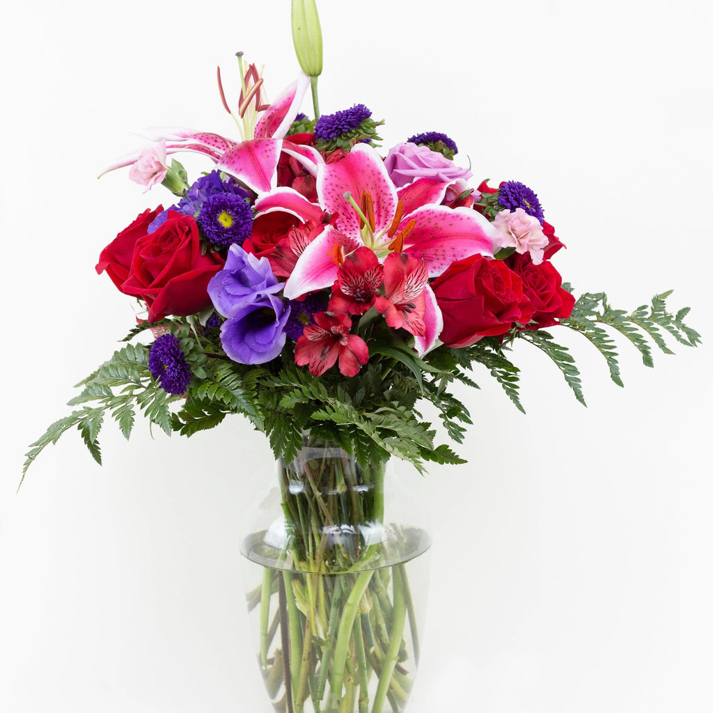 Array of Blooms -red roses , lavender carnations , red lilies , purple lisianthus , purple matsumoto asters , greens , vase arrangement