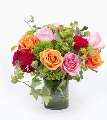 Lush Life Rose Bouquet Fuller - square vase filled with Hot pink, orange, and red roses capture the eye and the imagination accented with green trachelium, bupleurum, and ivy vines